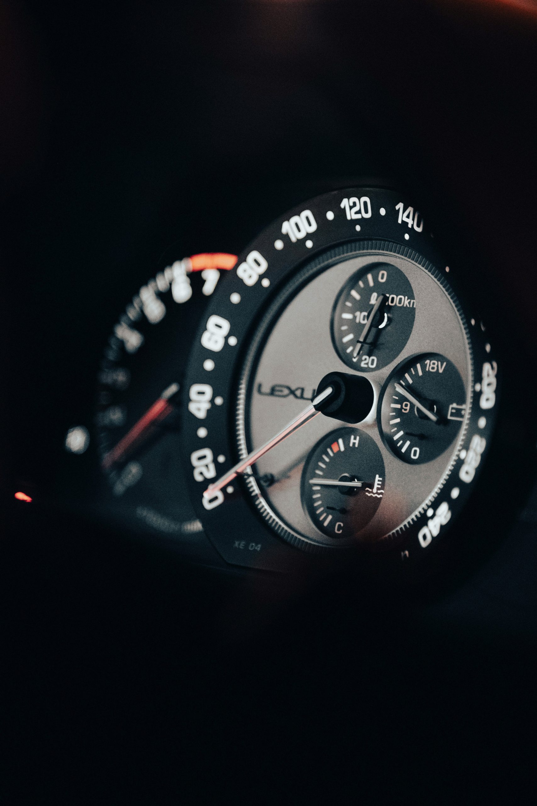 Een close‑up van het Lexus‑instrumentenpaneel met een snelheidsmeter tot 240 km/u, een voltmeter en een motortemperatuurmeter.
