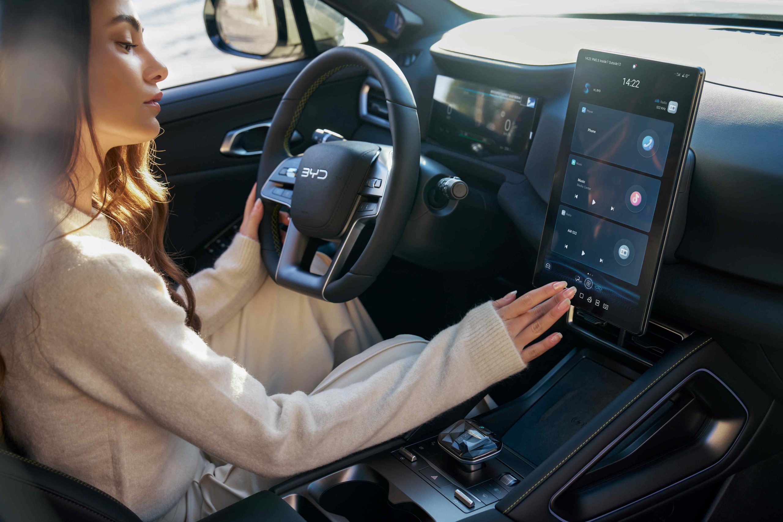 Interieur van een BYD‑auto met groot verticaal touchscreen waarop infotainment‑opties zichtbaar zijn.