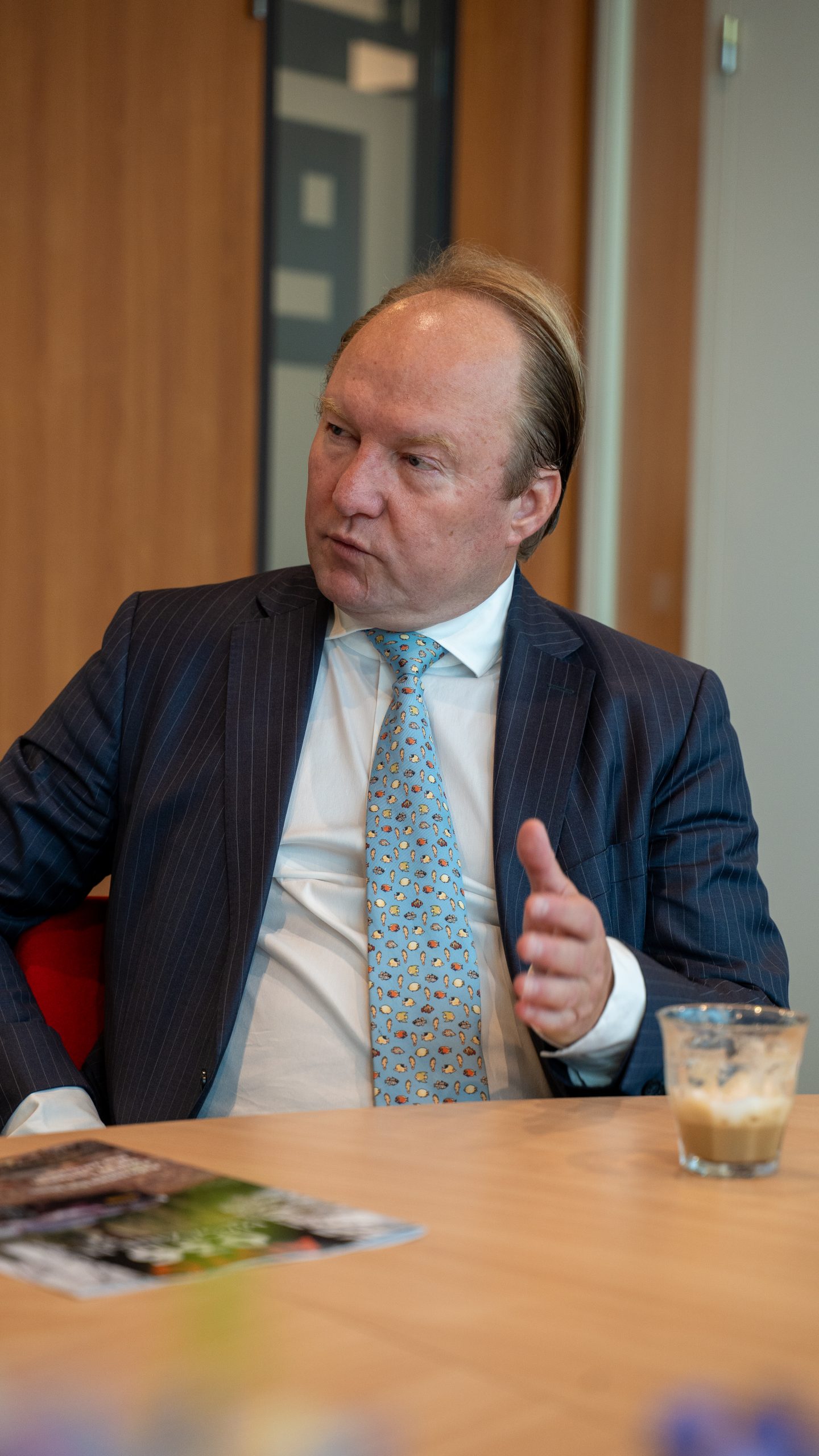 Man in pak aan tafel in gesprek.