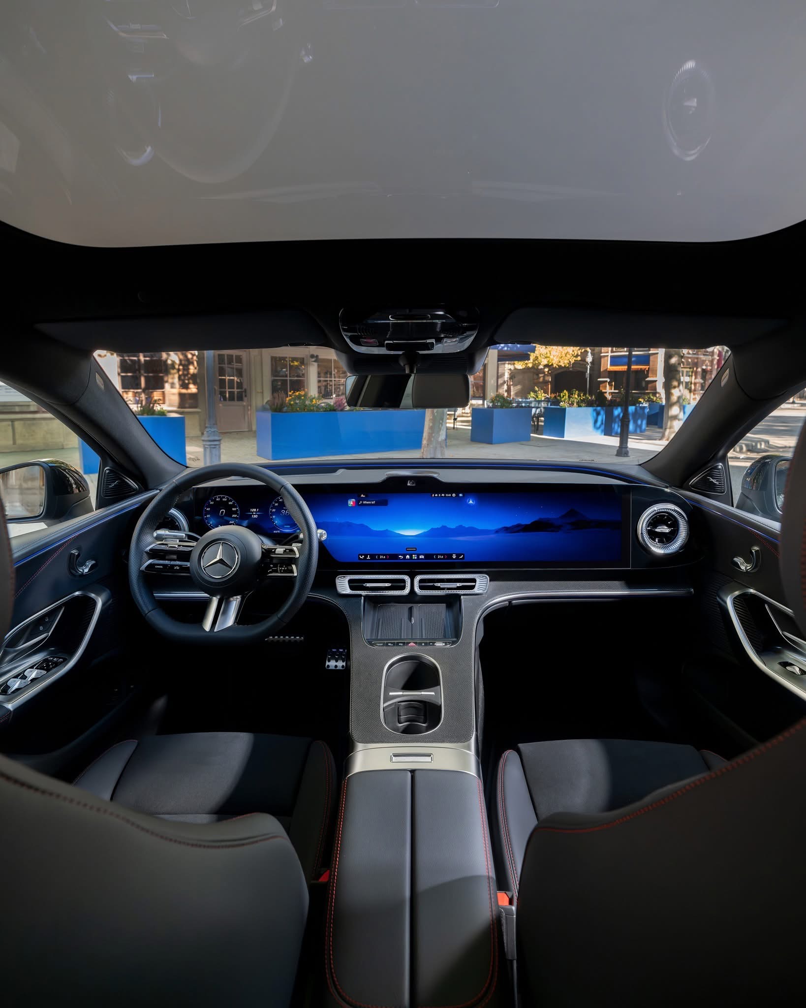 Luxueus Mercedes‑interieur met doorlopend digitaal display, lederen stoelen met rode stiksels en modern stuurwiel
