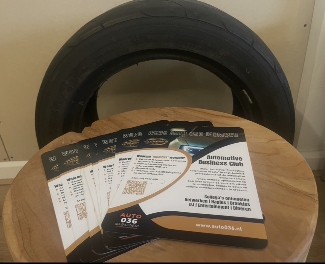 Promotietafel met Auto036‑flyers in een waaier voor een grote autoband, met informatie over het Automotive Business Club‑lidmaatschap en QR‑code voor meer details.