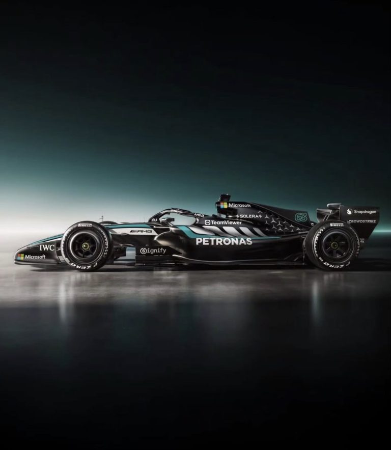 Een Mercedes‑AMG Petronas F1‑auto in zwarte livery met turquoise en zilveren accenten, nummer 63 op de zijkant, gefotografeerd op een reflecterende studiovloer.