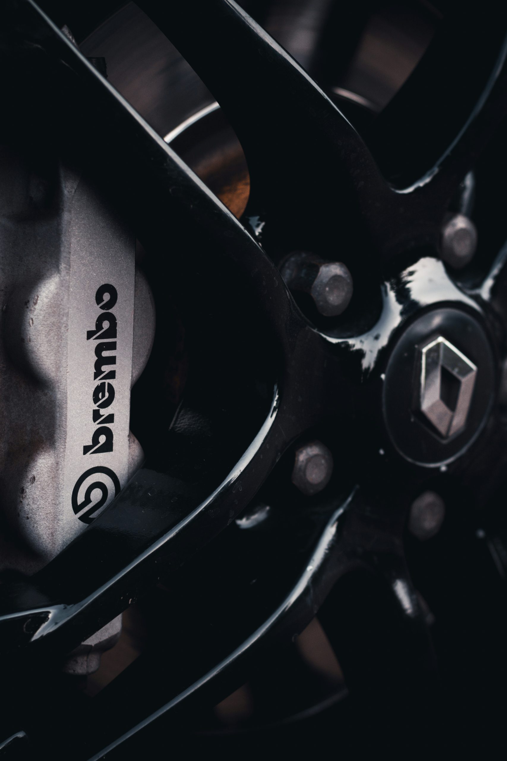 Een close‑up van een zilveren Brembo‑remklauw naast een glanzende zwarte Renault‑velg met logo in het midden.