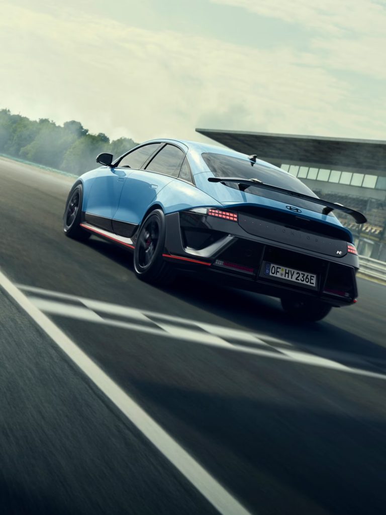 Voorwiel van een Formule‑1‑auto met Pirelli‑slickband, zwarte velg en blauwe body met diverse sponsorlogo’s.