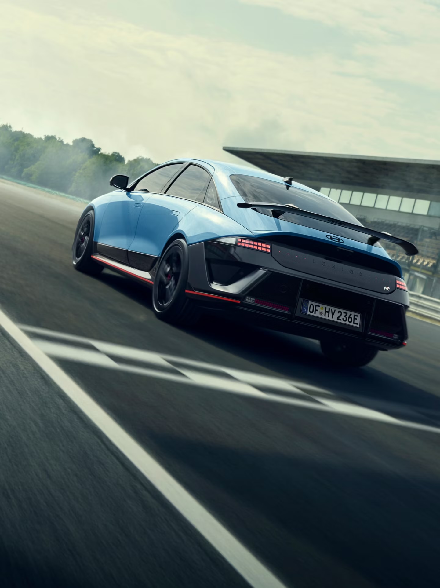 Voorwiel van een Formule‑1‑auto met Pirelli‑slickband, zwarte velg en blauwe body met diverse sponsorlogo’s.