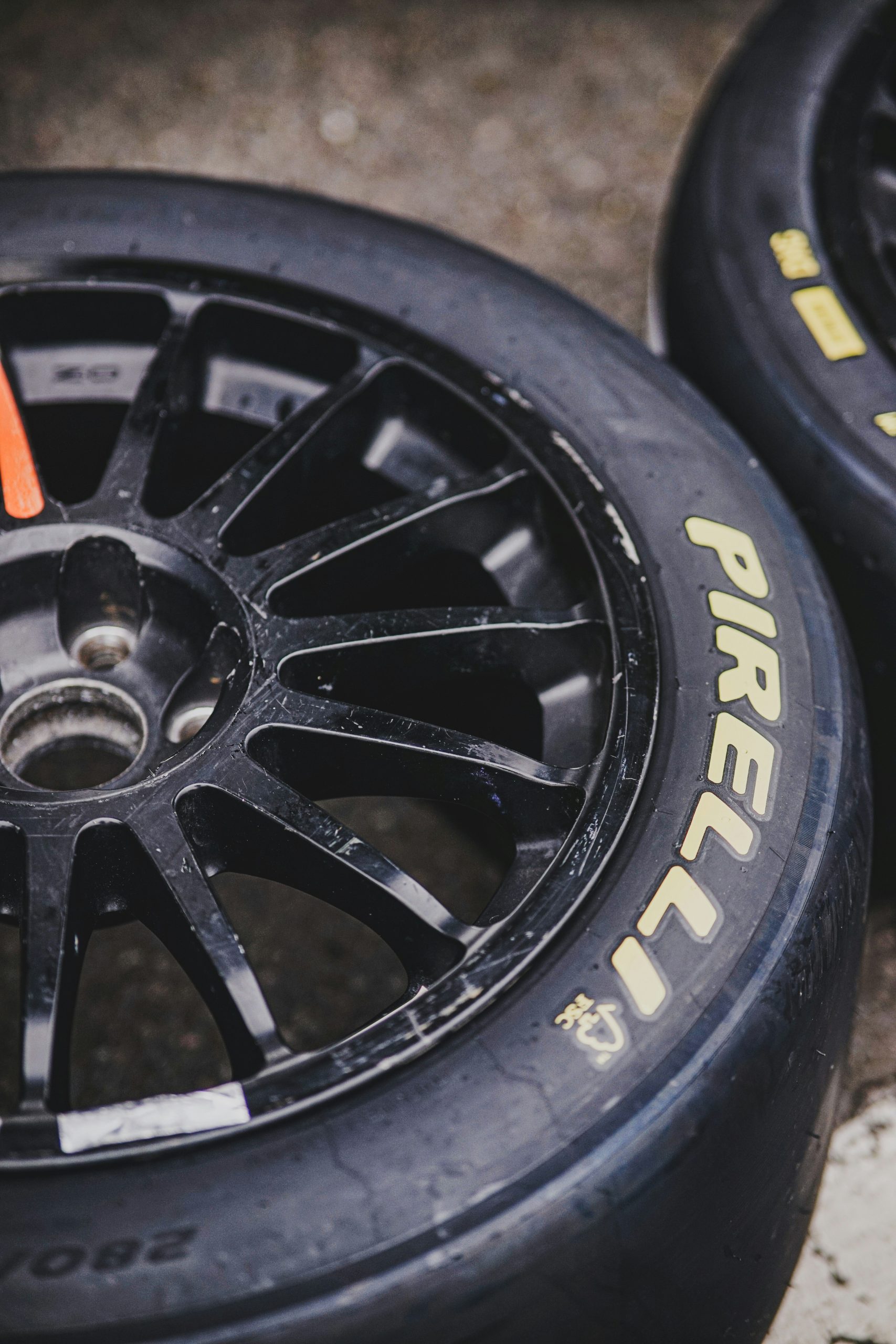 Close‑up van twee Pirelli‑slickbanden met zwarte meer‑spaaks velgen op een betonnen ondergrond