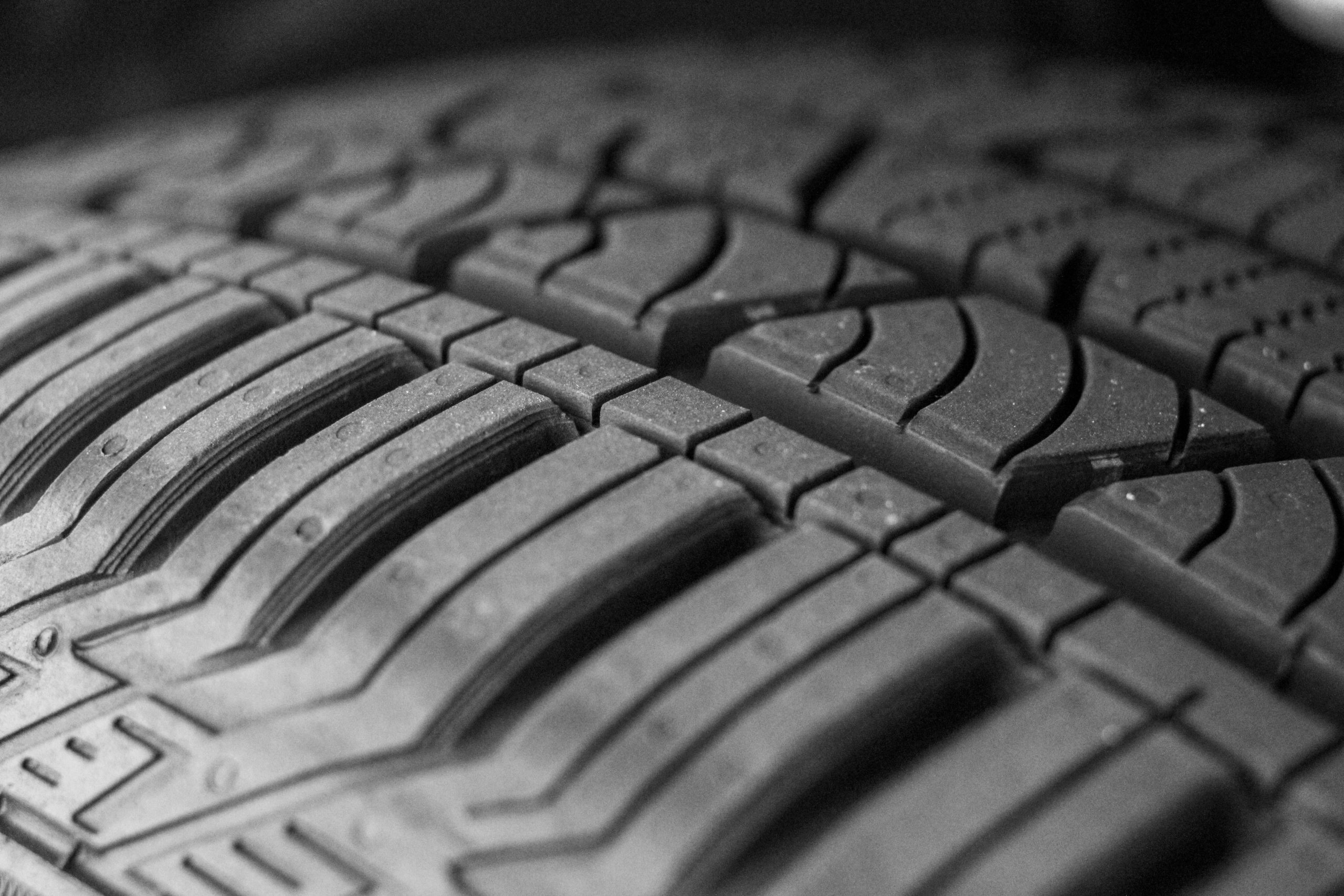 Zwart‑wit close‑up van een autoband met duidelijk zichtbaar profiel en diepe groeven