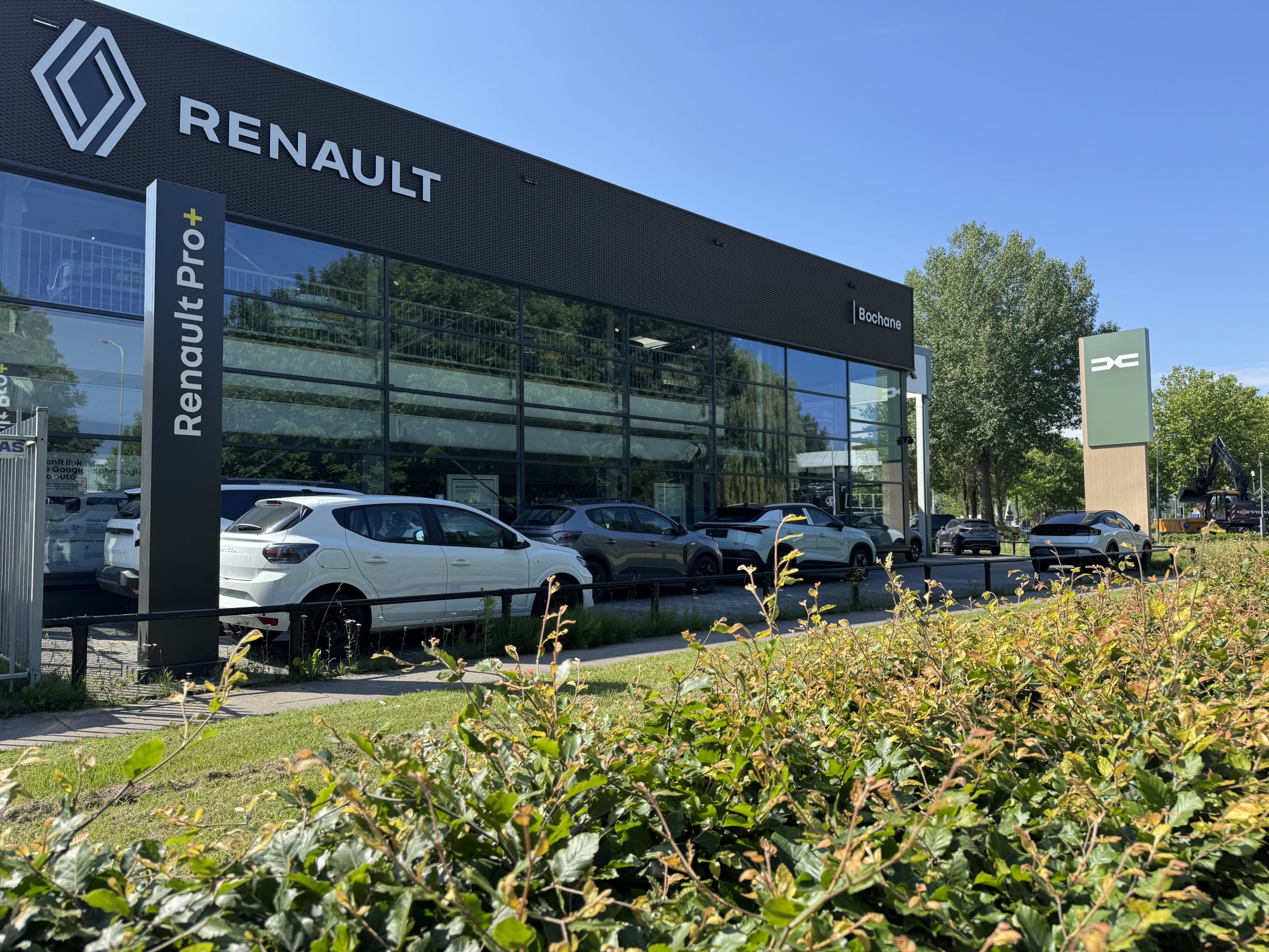 Moderne Renault en Dacia dealer Bochane met grote glazen gevel en meerdere auto’s voor de showroom.