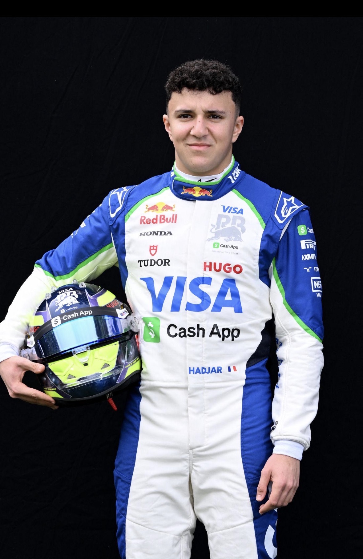 Coureur Isack Hadjar in zijn racepak met helm.