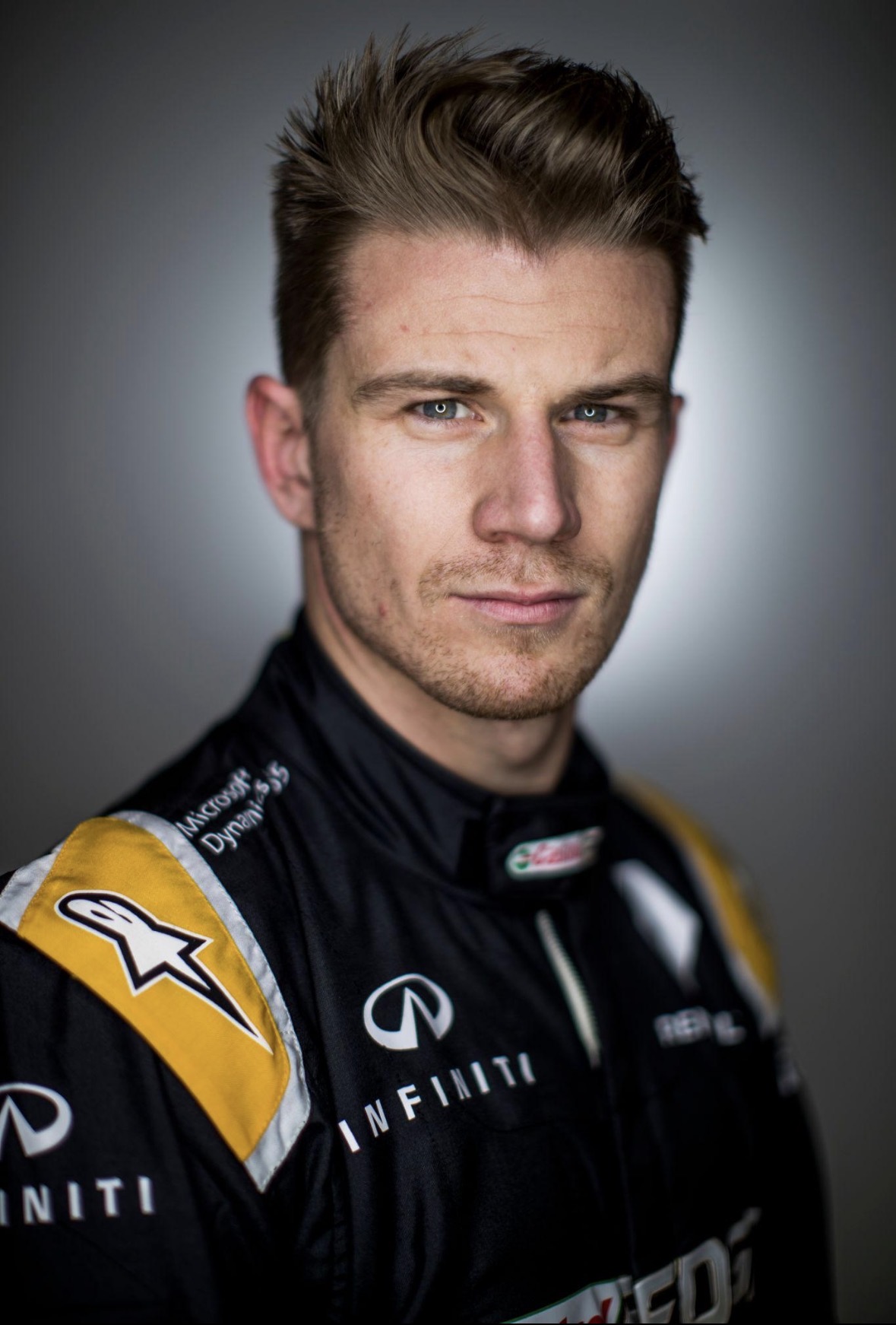 Portret van Nico Hülkenberg in zijn zwarte en gele Renault-racepak, met Infiniti-logo's zichtbaar.