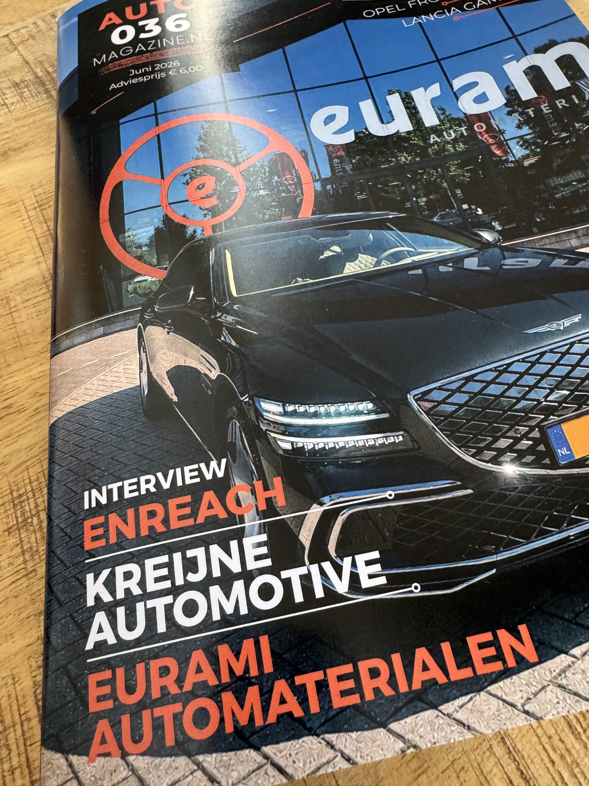 AUTO036 Magazine cover met zwarte luxe auto voor glazen gevel met Euram‑branding.