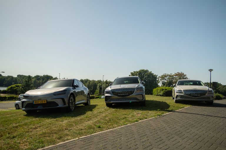 Drie Genesis elektrische modellen geparkeerd op gras bij water en bomen, inclusief Electrified GV70 en G80.